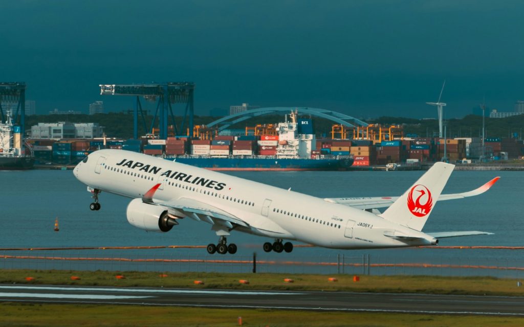 Foto Flugzeug mit Containerschiff und Hafen im Hintergrund